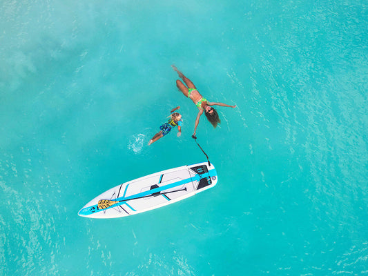 A woman swimming in the water with her child next to the Solo SUP paddleboard