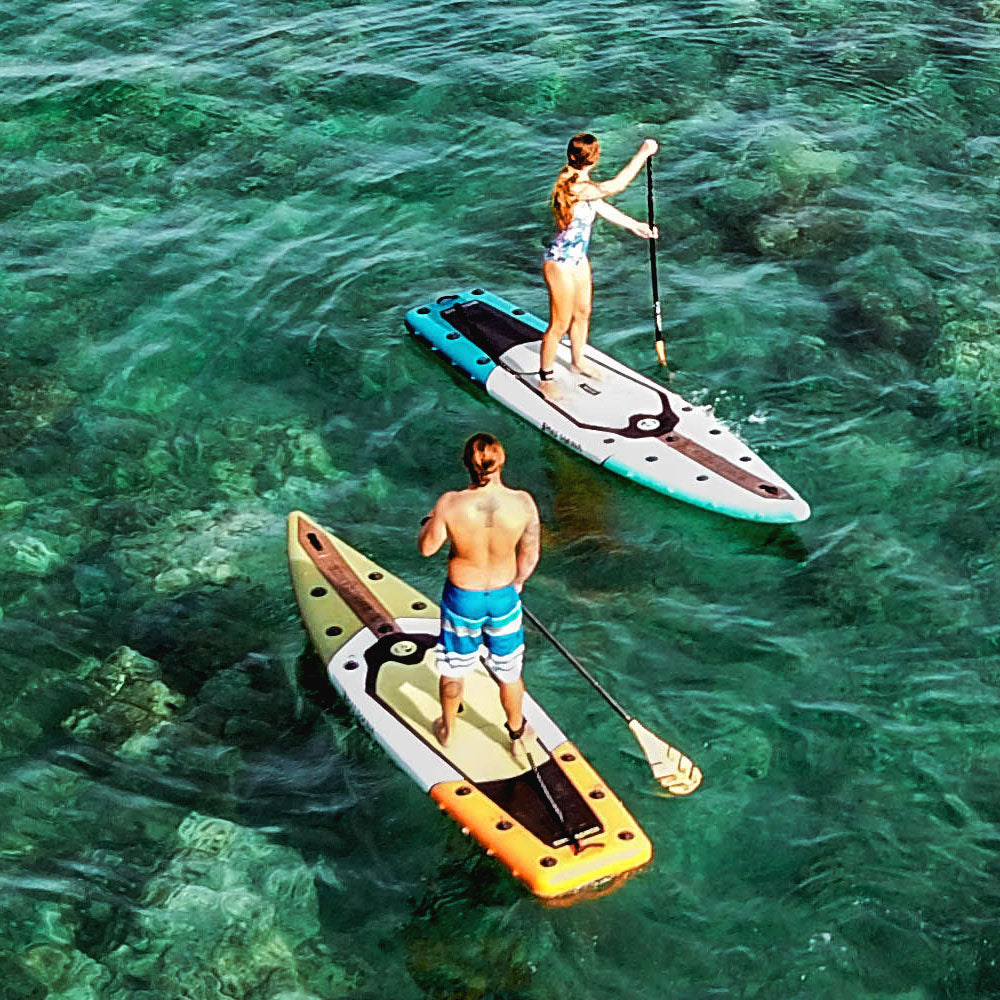 two people paddling on inflatable paddle boards on the ocean