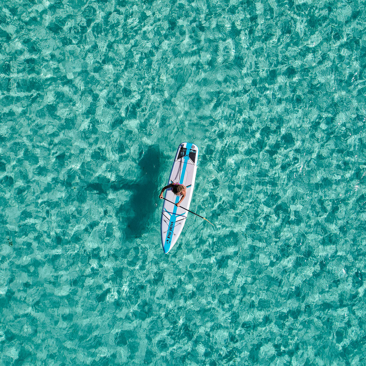 a woman paddling an inflatable paddleboard over clear blue waters