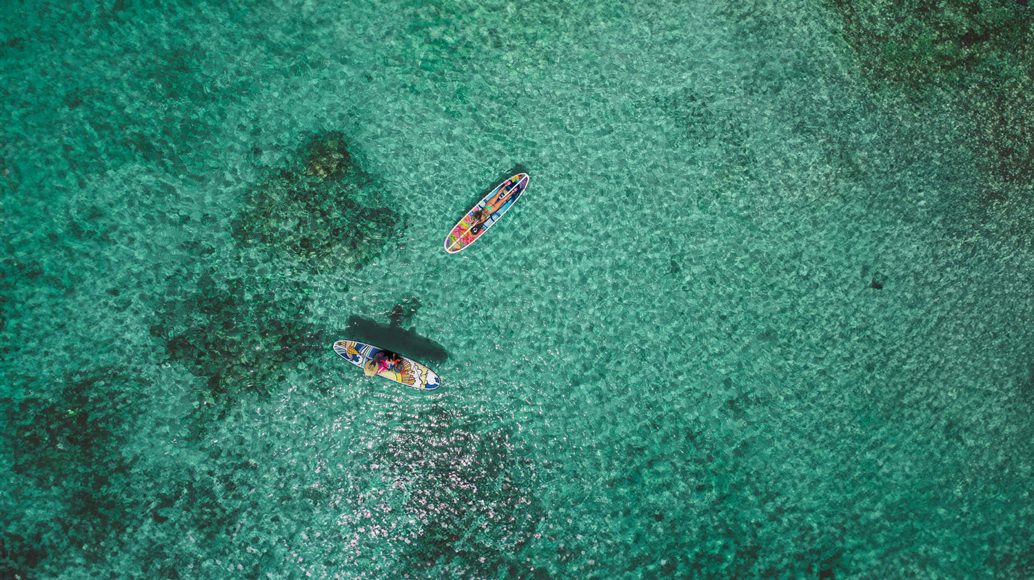 aerial image of two colorful paddle boards on the ocean