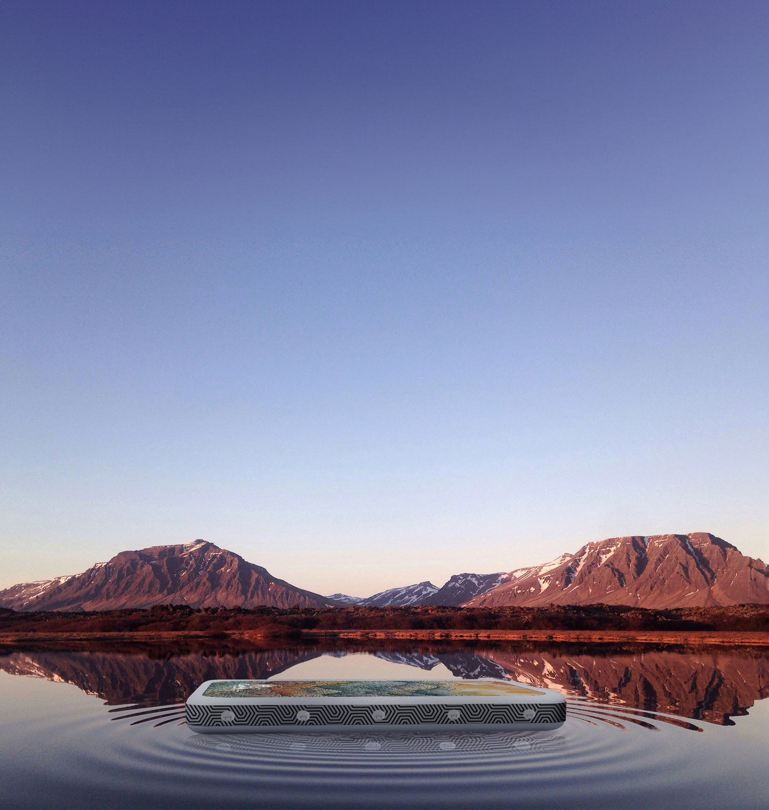 an inflatable surface on a lake at sunset with mountains in the background