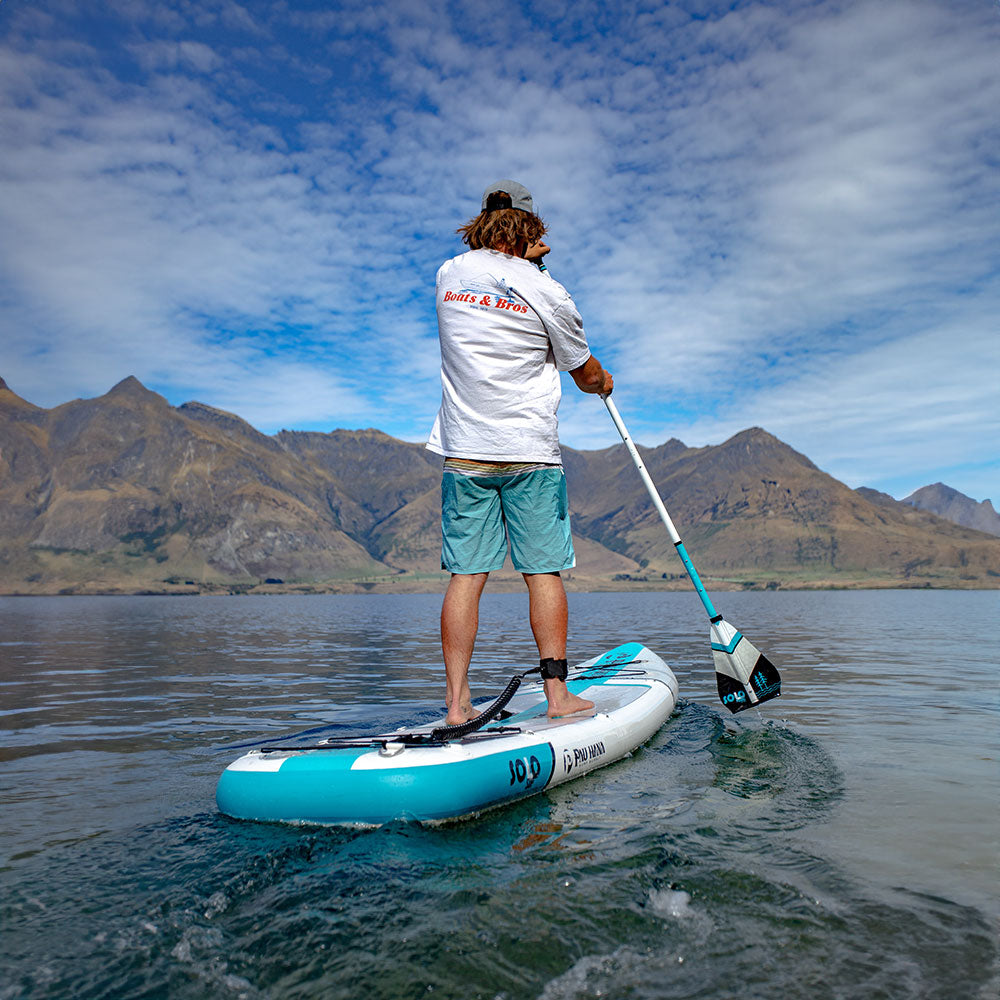 a man paddling an inflatable paddleboard on a lake in new zealand with mountains in the background