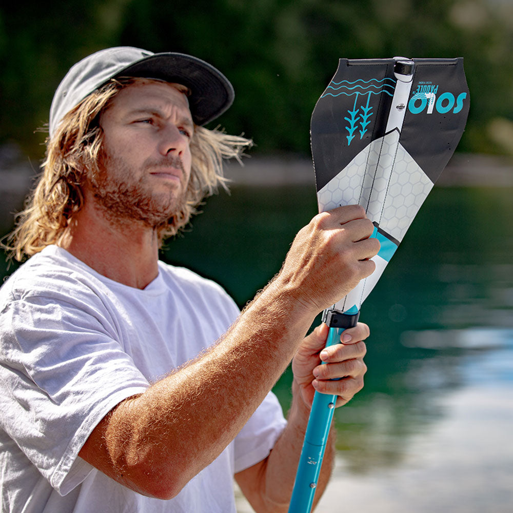 a man putting together the soft blade solo sup sup paddle with a lake in the background