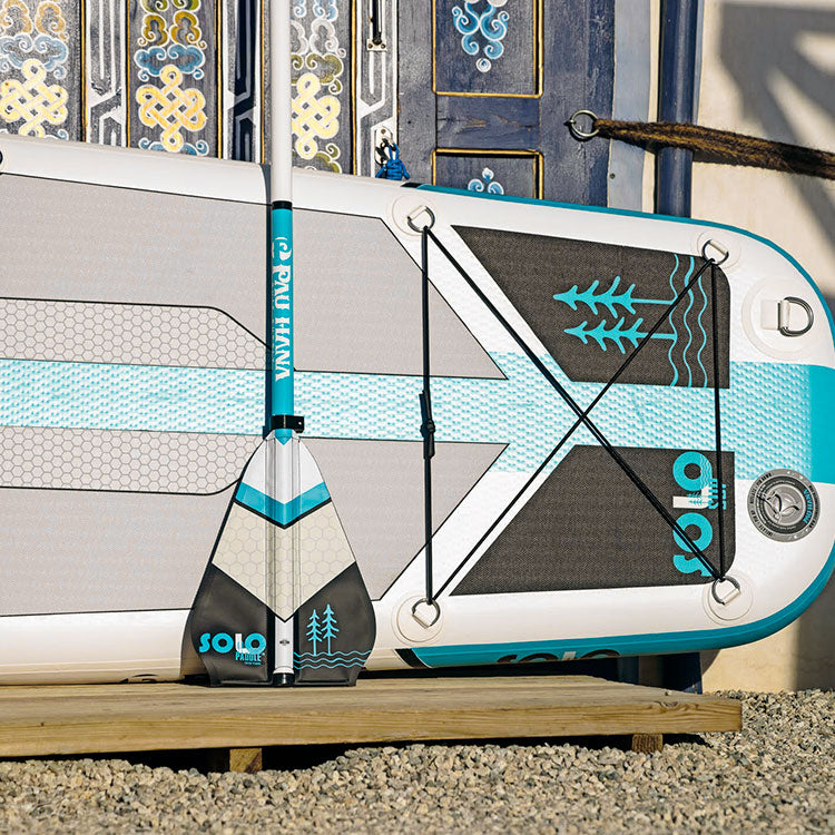 the solo sup paddle ad inflatable paddle board leaning against a pretty door