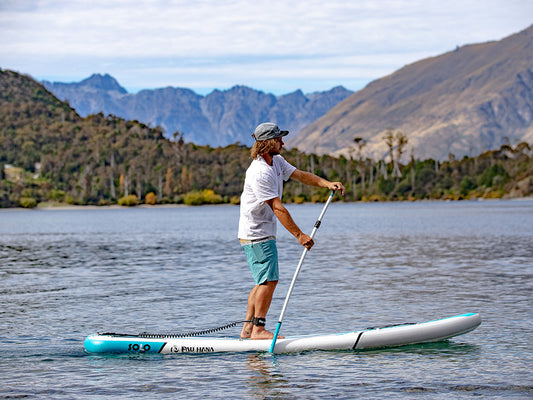 a man paddling a paddle board on a lake in queenstown new zeland