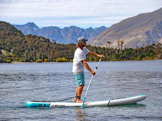 a man paddling a paddle board on a lake in queenstown new zeland