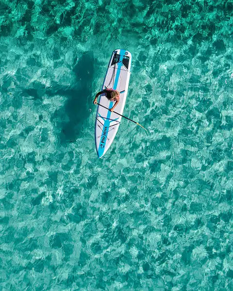 Person paddleboarding on clear turquoise water