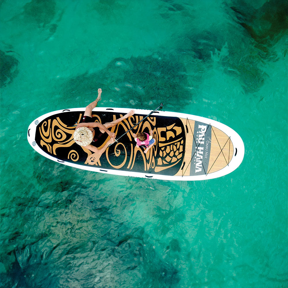 an aerial image of a man and child sitting on a giant inflatable paddleboard on the ocean