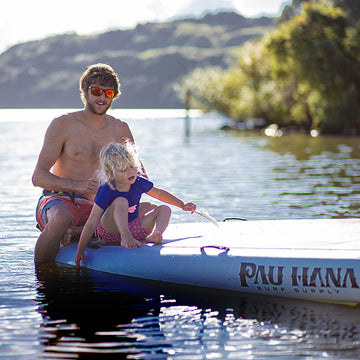 Family having fun on a giant paddleboard on a lake in New Zealand