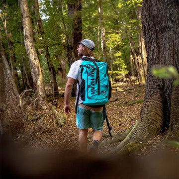 Man hiking in a forest with a blue backpack