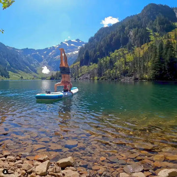 Person doing a handstand on a paddleboard in a mountain lake