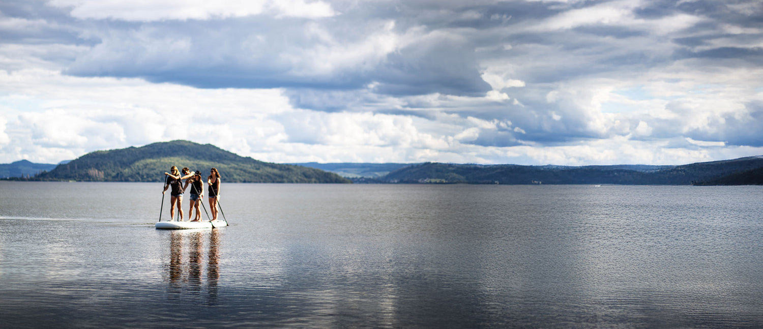 Group of people paddleboarding on a lake with mountains in the background