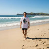 Man walking on a sandy beach with ocean and mountains in the background