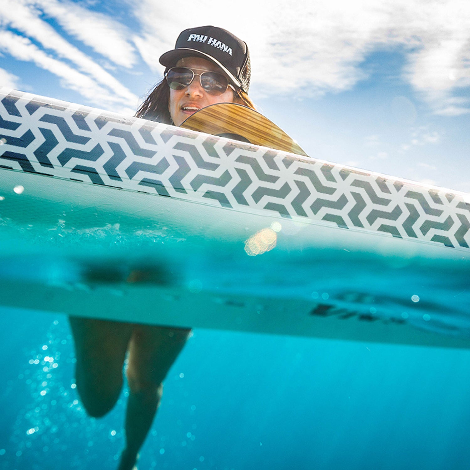 a woman swiming in the ocean holding onto an inflatable paddleboard