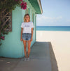 Woman standing in front of a turquoise building with ocean view